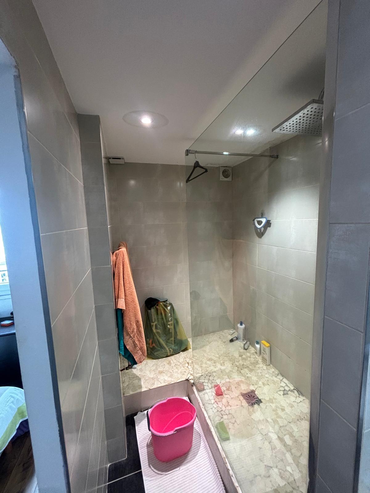 Douche à l'italienne en galets avec paroi fixe et ciel de pluie
