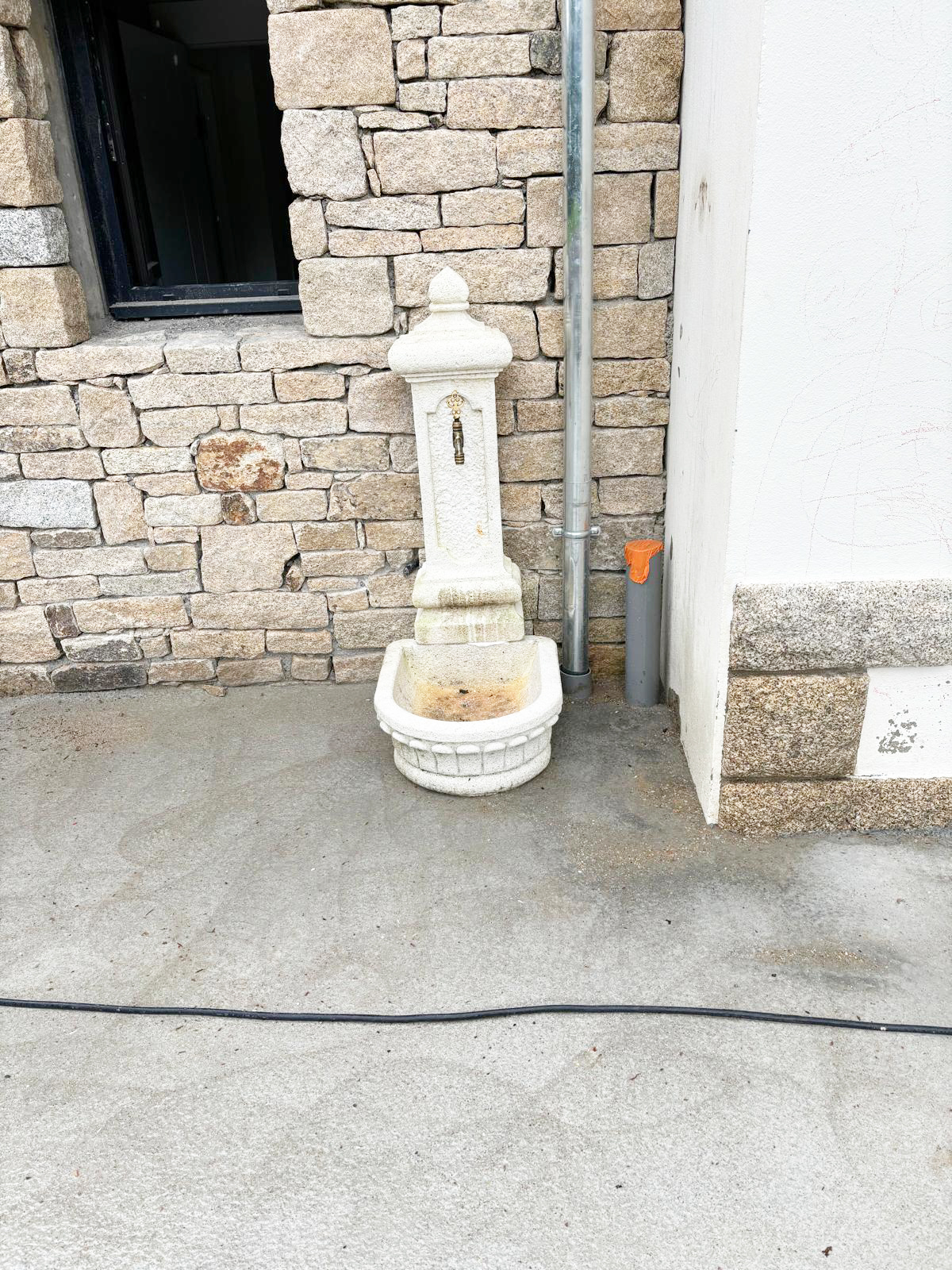 Fontaine de jardin raccordée sur un mur en pierre