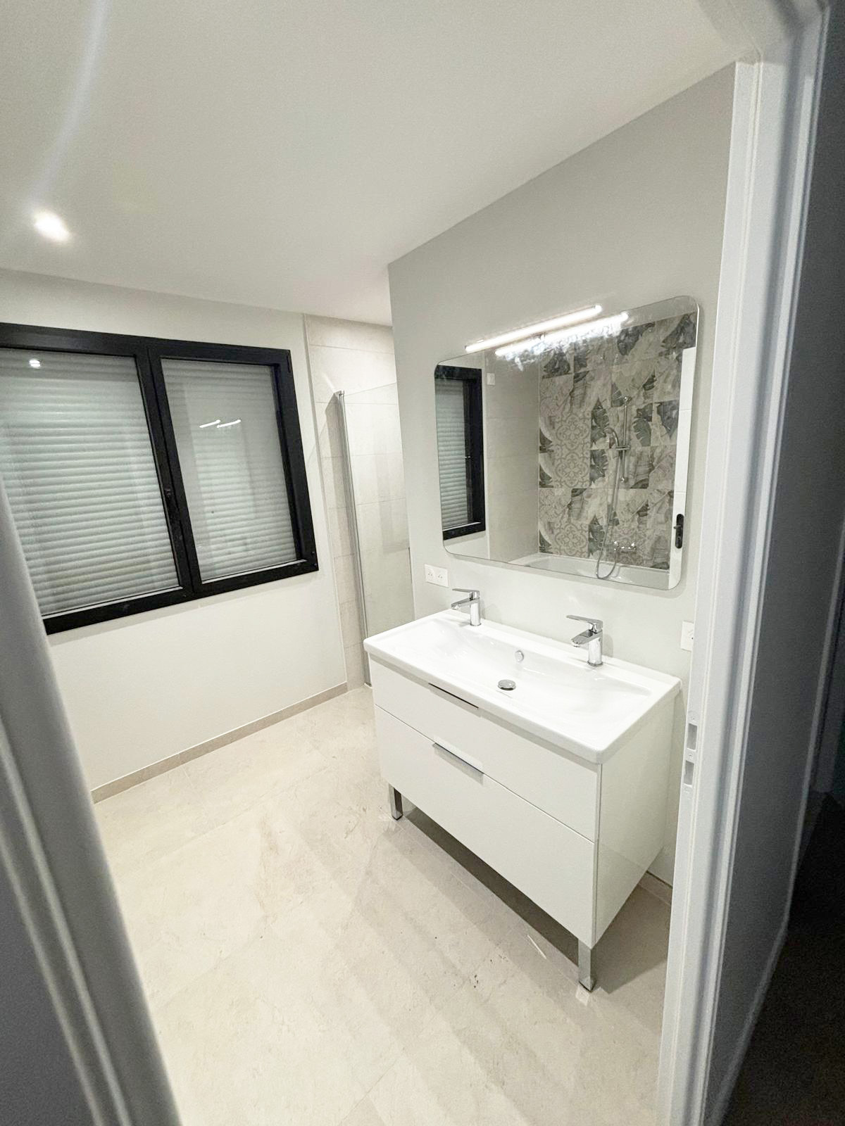 Salle de bains double vasque blanche, miroir lumineux et douche en carreaux de ciment